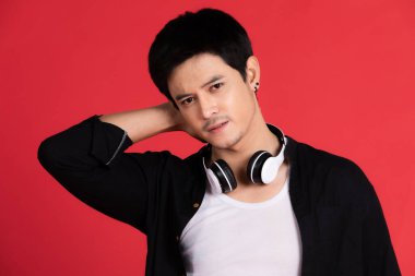 Yakışıklı, gülümseyen Asyalı bir adam kulaklıkları boynunun iki tarafına asıyor. Ve ağzının köşesinde gülümsedi.