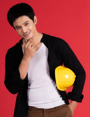 Asyalı yakışıklı genç mühendis pirinç yankesicileri ile dur ve stüdyonun yan tarafına sarı bir güvenlik kaskı tak..