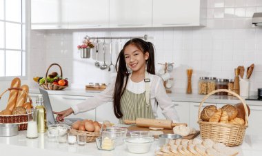 Genç Asyalı kızlar hamur yoğurma pratiği yapıyorlar. İnternet ve bilgisayardan yemek tarifleri bul. Mutluluk ve gülümsemeyle Evdeki mutfağın içinde