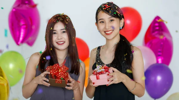 カラフルなコンフェッティの下にギフトボックスが立っている楽観的な若いかわいいアジアの女性は 休日のお祝いの間にカメラと笑顔を探しています 楽しい時間を共有し 祭りの概念を祝う — ストック写真