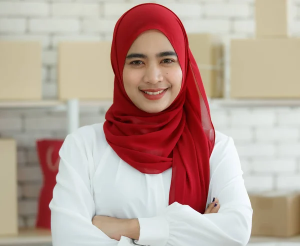 オフィスに立っている赤いヒジャーブを着た可愛い笑顔のムスリム女性がカメラを見て腕を交差させている姿が描かれています 自信に満ちた十代の実業家の概念 — ストック写真