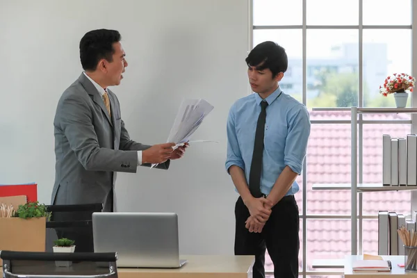 Asian businessman manager in suit throwing paperwork into air and blaming for young employee with anger and serious gesture. Office work problem and job quality conflict concept