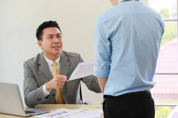 Asian businessman manager in suit holding paperwork and blaming for young employee with anger and serious gesture look like he comments as disagree or unacceptable for his project work.