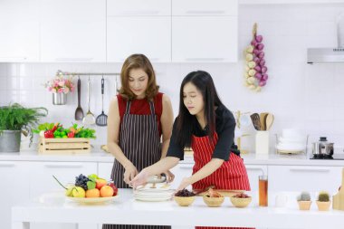 Mutlu etnik ev hanımları evdeki mutfakta öğle yemeği için çeşitli lezzetli yemeklerle servis yapıyorlar..