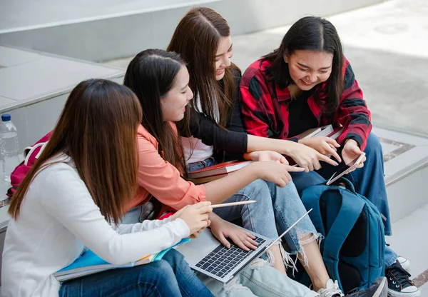 Group of four young attractive asian girls college students studying together in university campus outdoor. Concept for education, friendship and college students life.