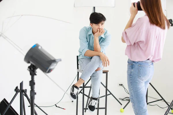 아시아의 우호적 미소는 카메라를 스튜디오에서 렌즈에 가까운 의자에 잘생긴 모델을 — 스톡 사진