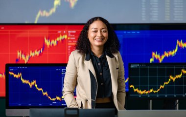 Başarılı kadın borsa simsarı gülümse ellerini pantolonunun cebine koy bilgisayar monitörü ekranındaki kameraya bak hisse senedi ve bitcoin kripto grafik analizi.