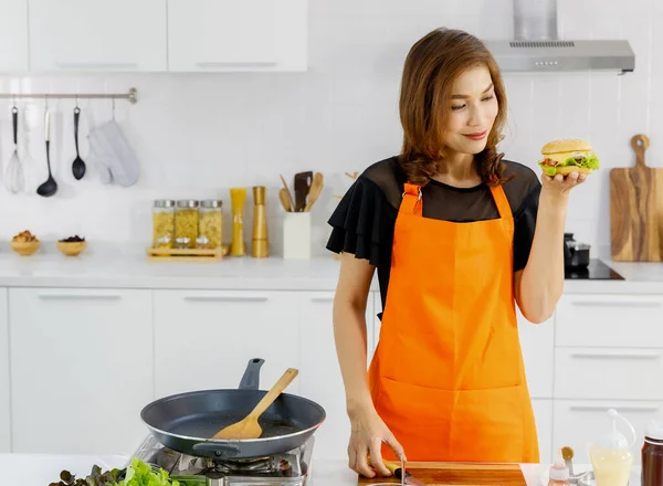 매력적 미녀는 주황색 앞치마를 현대식 가정집 부엌에 플라잉 웃으며 손에는 — 스톡 사진