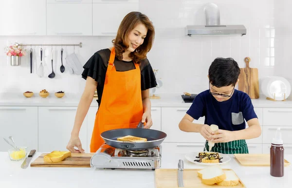 주부로서 오렌지 앞치마를 미소를 엄마는 아이들에게 현대식 주방에서 우유로 빵굽는 — 스톡 사진