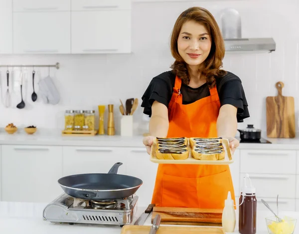 오렌지 앞치마를 기구에 미소를 초콜릿 크림으로 토핑하는 맛있는 쟁반을 아시아 — 스톡 사진