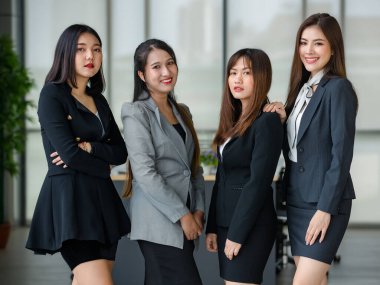 Resmi takım elbiseli dört çekici Asyalı bayan ofis arkadaşı kameraya gülümsüyor. Modern ofis çalışması kavramı.