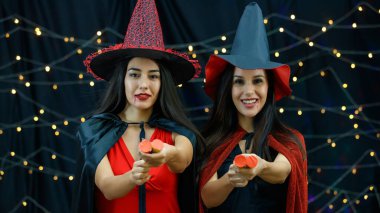 Şık cadı kıyafetleri içinde heyecanlı genç kızlar ve Cadılar Bayramı kutlamalarında krakerleri yılanbalığıyla patlatan şapkalar