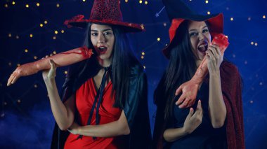 Cadılar Bayramı kutlamaları sırasında ellerinde yapay kanlı insan kolları olan ürkütücü makyajlı genç kızlar.