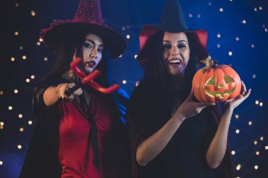 Cadılar Bayramı kutlamalarında kameraya şeytan mızrağıyla bakan balkabağı kafalı neşeli genç bayan.