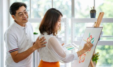 Üst düzey erkek ve kadın çift, karı koca, sıcak ve mutlu bir şekilde ev galerisinde resim yapıyorlar. Adam kadına sevgi ve özenle sarılır ve dokunur..