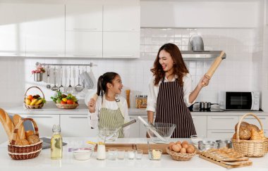 Asyalı bir anne elinde oklavayla mutlu mesut fırın oynuyor ve evdeki modern mutfakta pasta öğreniyordu. Aşk ve bağ kavramı