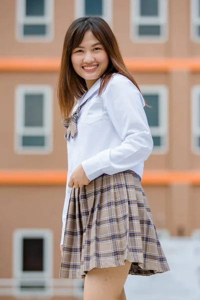若いです長いです肖像画の若いです魅力的な女性アジアの高校生で白いシャツ茶色小学校制服アームクロスで学校のキャンパス笑顔 — ストック写真
