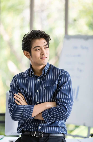 Asian handsome successful male businessman standing smiling in front of sales and marketing meeting whiteboard with graph chart data information in office room at company.