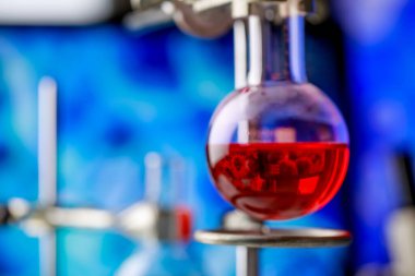 Patojenik mikroorganizmayı veya virüsü teşhis etmek için bilimsel deney amacıyla kimyasal cam şişenin içindeki kırmızı reaksiyonlu çözeltiye bilgisayar ekranından yansıyan mikrop..