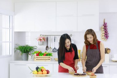 Mutlu etnik ev hanımları evdeki mutfakta öğle yemeği için çeşitli lezzetli yemeklerle servis yapıyorlar..