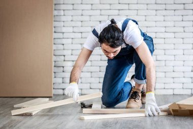 Tamirci olarak çalışan genç hippi Asyalı adam ahşap masayı malzemelerle birleştiriyor, ev yapımı konsept ve evde self servis yapıyor..