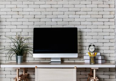 Daha az dekore edilmiş ofis konçertosu, metal raf, bilgisayar direktörü sandalyesi ve tuğla kaplamalı ahşap masa. Evde çalışma kavramı.