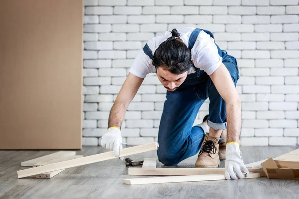 Tamirci olarak çalışan genç hippi Asyalı adam ahşap masayı malzemelerle birleştiriyor, ev yapımı konsept ve evde self servis yapıyor..