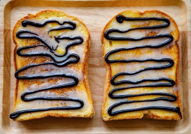 Masadaki bambu tepsisine çikolata soslu lezzetli tostların en üst görüntüsü.