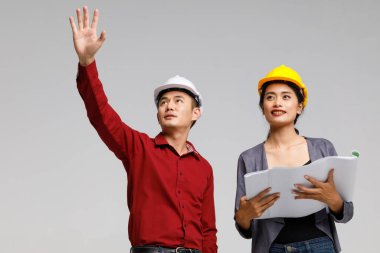 Stüdyoda gri arkaplan projesinden bahsederken kağıt taslağı olan Asyalı mühendislerin düşük açılı görüntüsü