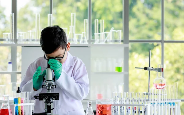 Asijský Školák Brýle Laboratorní Plášť Zkoumá Chemickou Látku Mikroskopem Při — Stock fotografie