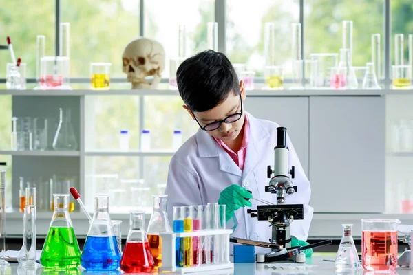 実験室での化学研究中に実験を行いながら 顕微鏡レンズの下に滴状の液体サンプルを注ぐ研究室のコートと手袋に集中スマートアジアの少年 — ストック写真
