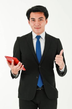 Zeki genç Asyalı iş adamı ya da girişimci resmi siyah takım elbise giyip elinde dijital tablet bilgisayarla beyaz arka planda dikiliyor..