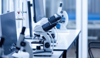 Coronavirus covid 19 virüs örneğini izlemek için laboratuvar çalışma masasında ön planda bulanık bir şekilde duran iki göz görüşlü bilimsel mikroskobu yakından çek..