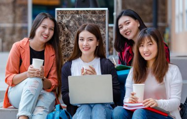 Sırıtkan Asyalı kız öğrencilerin üniversite kampüsünde dinlenip kameraya baktığı bir şirket. Yakın ve samimi arkadaş kavramı.