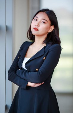 Şık giyinmiş kararlı Asyalı kadın girişimci ofis salonunda kollarını kavuşturup kameraya bakıyor.