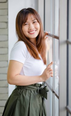 Sevimli içerikli yarım uzunlukta bir portre çekici esmer kadın şık, sıradan bir elbise giymiş ve arkadaş canlısı, pozitif ve kendine güvenen pozuyla poz veriyor..