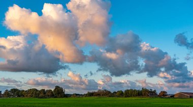 Yükselen güneş sayesinde, Zoetermeerse Gölü boyunca uzanan bu çiftliklerin üzerindeki bulutlar çok güzel renklerde.