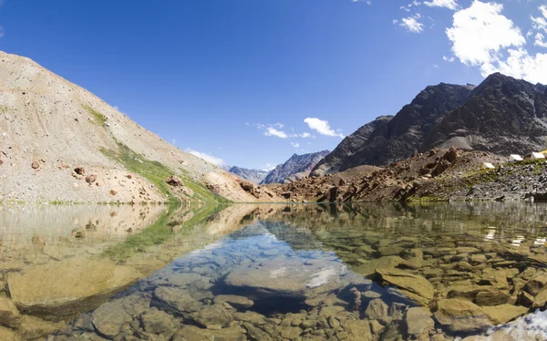 Lago de montanha com as belas reflexões na água da natureza circundante e céu azul no dia ensolarado de verão — Fotografia de Stock