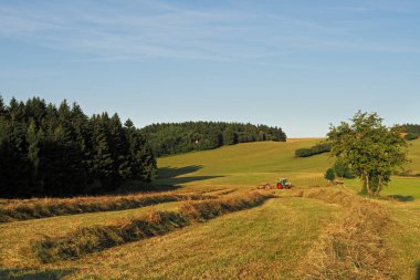 Agricultural machine during work on a small foothill meadow