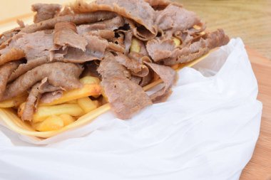 Tahtada patates kızartması ve et parçaları var.