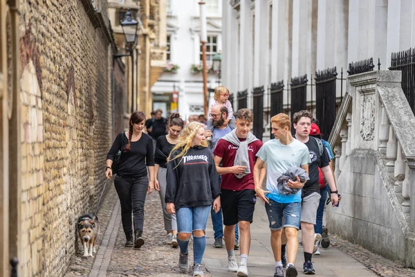 Kings Üniversitesi önünde güneşli bir günde Cambridge caddesinde yürüyen turistler. Cambridge, İngiltere, 1 Ağustos 2019.