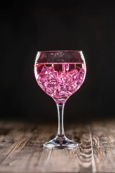 Келих з рожевим коктейлем, наповнений льодом на темному фоні — стокове фото