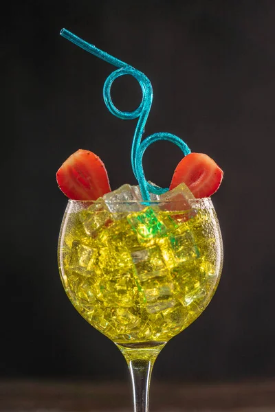 Желтый коктейль в наполненном льдом стакане, украшенном клубникой с голубой кудрявой партией — стоковое фото