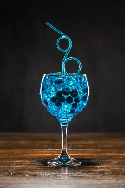 Синій коктейль з чорницею та льодом у склянці на дерев'яному столі — стокове фото