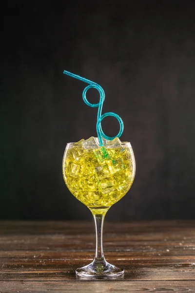 Желтый коктейль в наполненном льдом стакане, украшенном клубникой с голубой кудрявой партией — стоковое фото