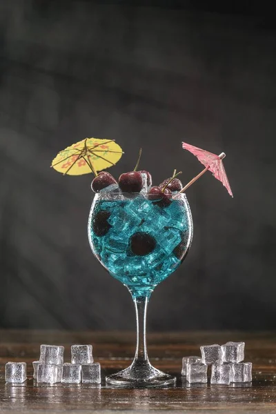 Голубой коктейль в стакане со льдом и вишней — стоковое фото