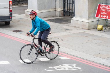 Bisikletli bir adam yaya geçidinde arka plan tabelasına karşı karşıya geçiyor. Mesafeyi koruyun. İngiltere, Londra, 29 Mayıs 2021