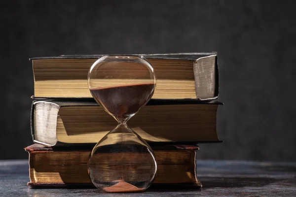 A stack of old books and an hourglass. The concept of time and knowledge — Stock Photo, Image