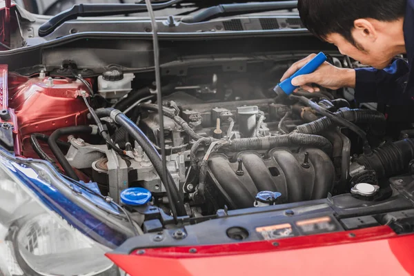 アジアの男の整備士の検査エンジンのトーチカーエンジンチェックバグを輝きます 自動車エンジンでサービスメンテナンス保険のための青い車 — ストック写真