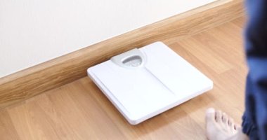 Pantolonlu erkek bacaklarının odada tartıya çıkışının yavaş görüntüleri. 